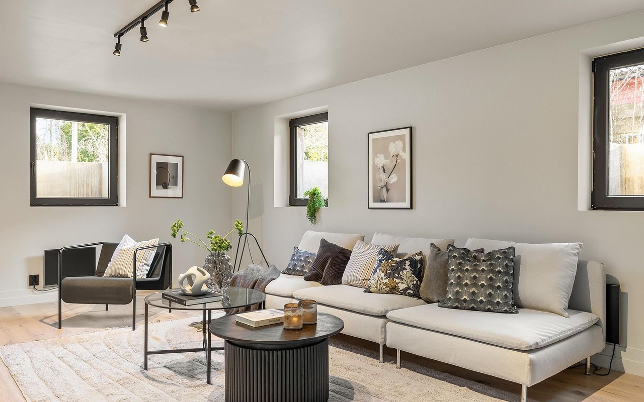 Living room with a white sectional sofa, dark accent chair, and three black-framed windows.