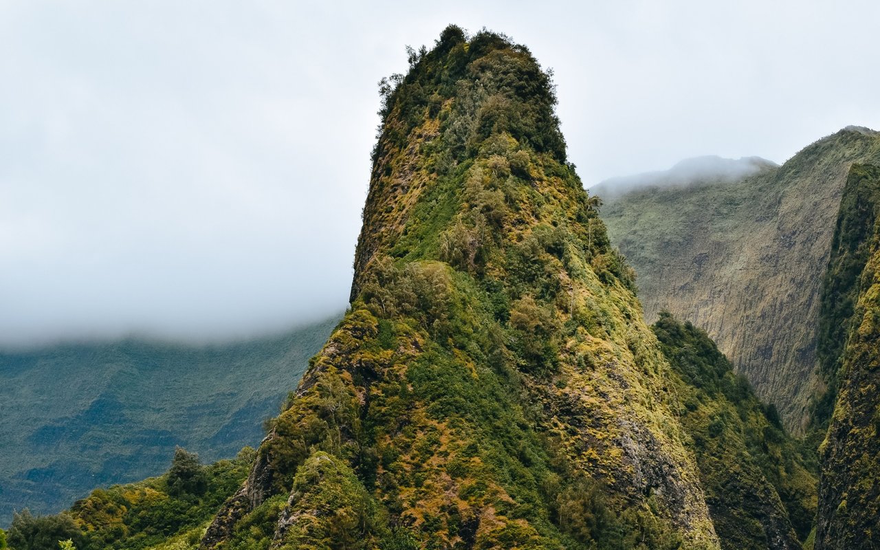 Olomana’s steep, green peak rises among cloud-covered ridges in Kailua.
