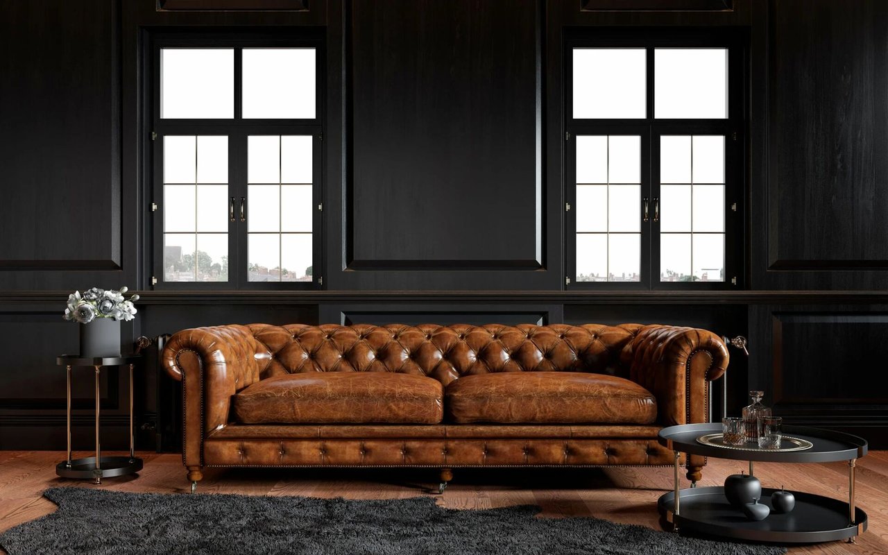 Dark paneled living room with a tufted cognac leather sofa and tall divided-light windows.