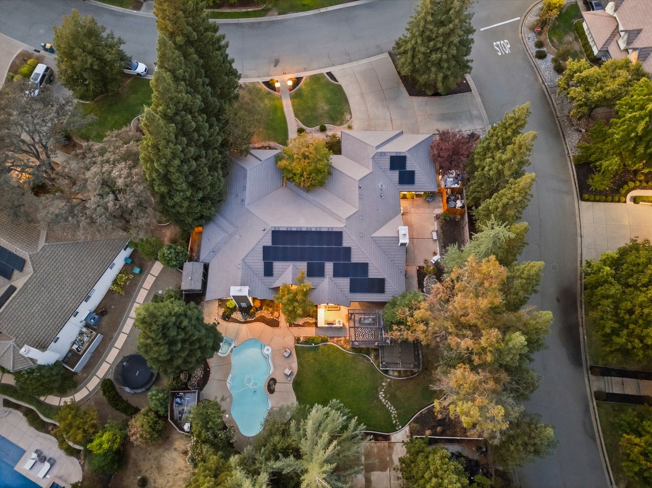 Aerial view of a home with rooftop solar panels, a swimming pool, and landscaped grounds.