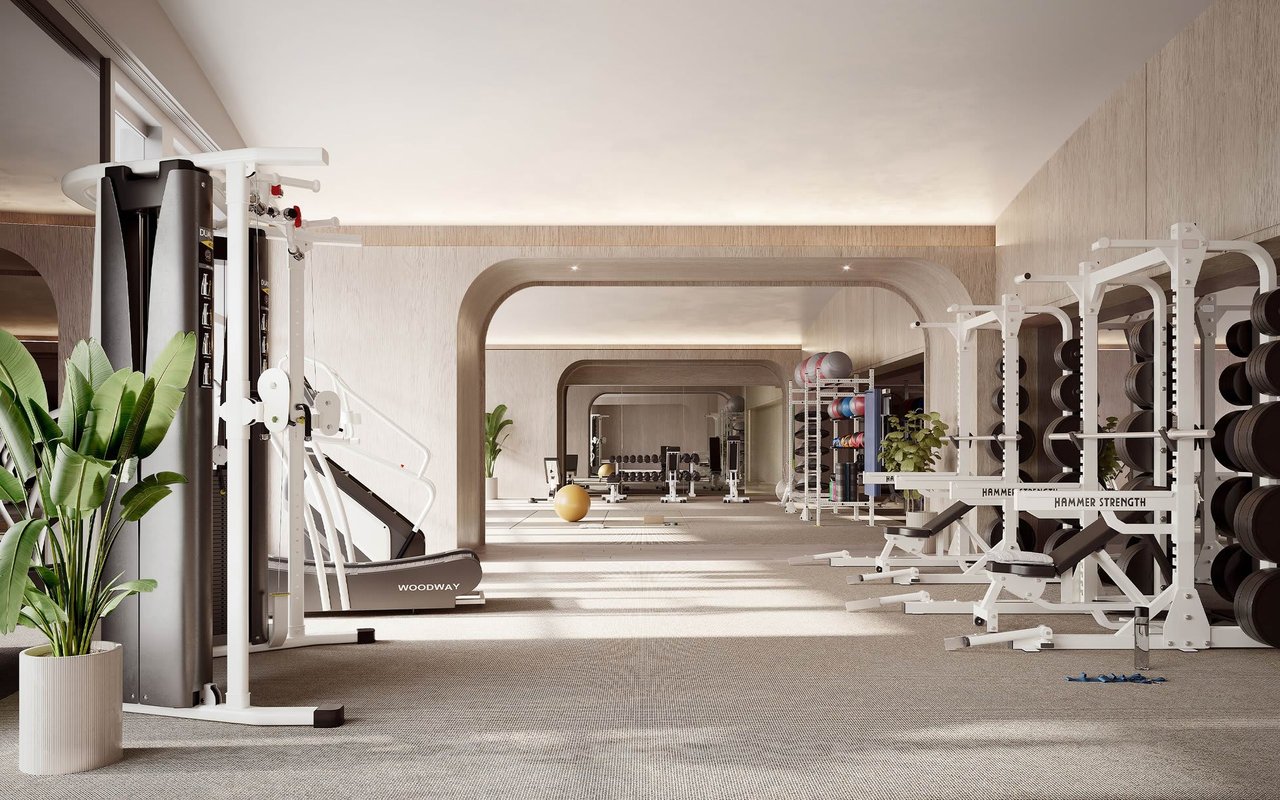 Modern residence gym with strength machines, weight racks, and repeating arched openings.