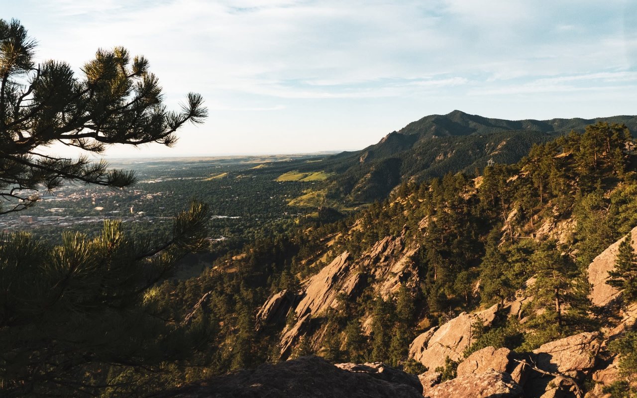 A view from the top of a mountain, looking out at a range of other mountains and a valley below