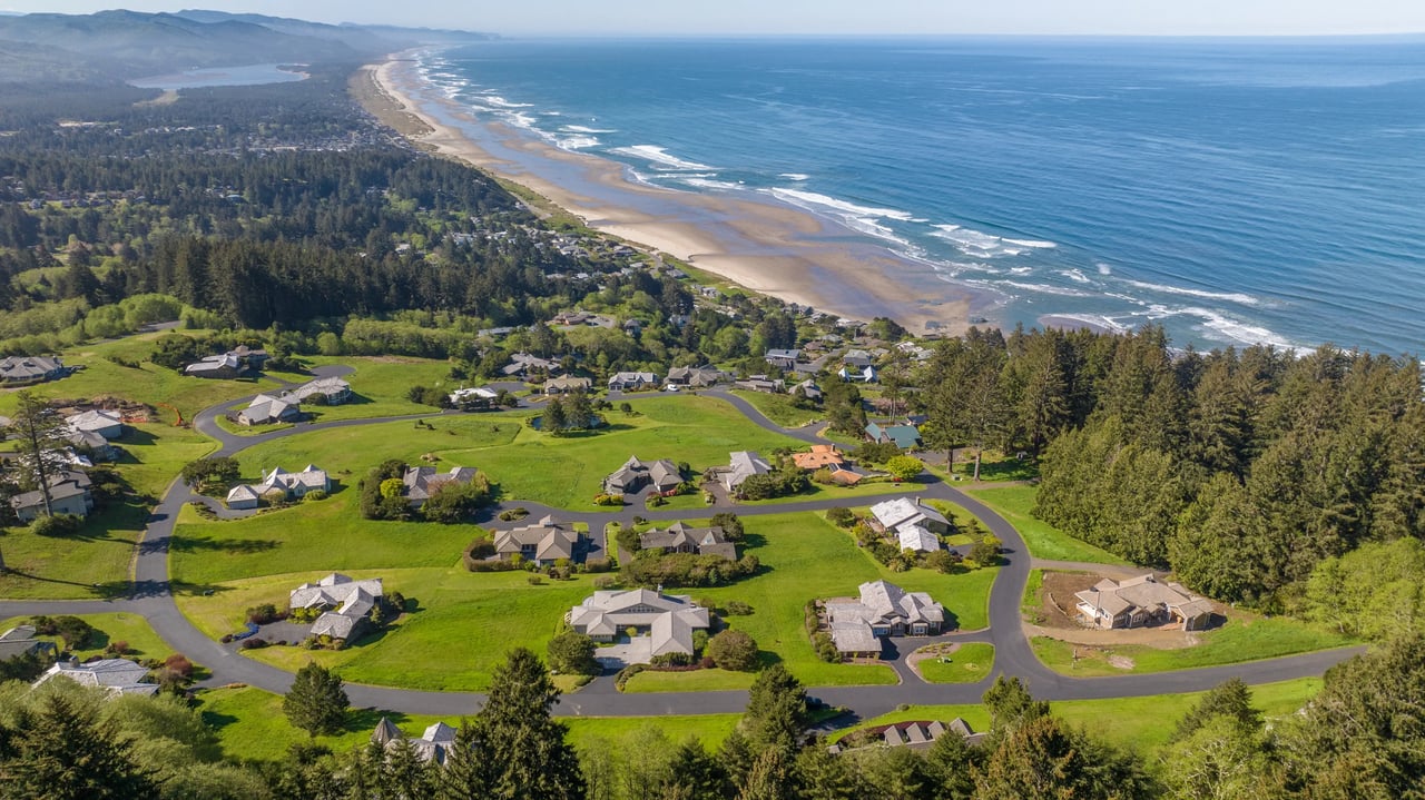 aerial view of bright green fields and homes overlooking the deep blue pacific in neahkahnie