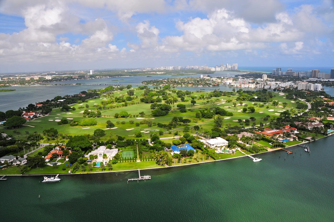 Aerial view of a golf course and houses on an island in the middle of the ocean