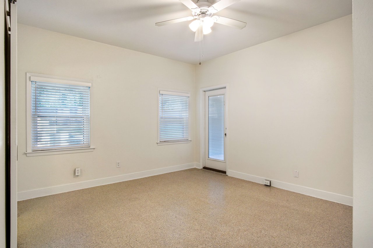 Another view of the primary bedroom, showing built-in storage and large windows. The room is bright and spacious.