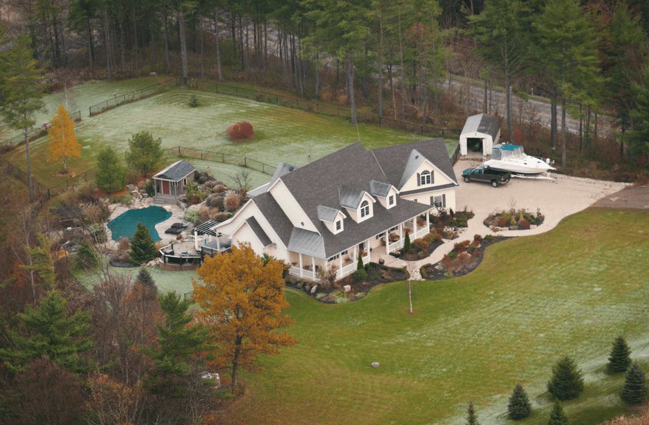 An aerial view of a house with a boat in its driveway.