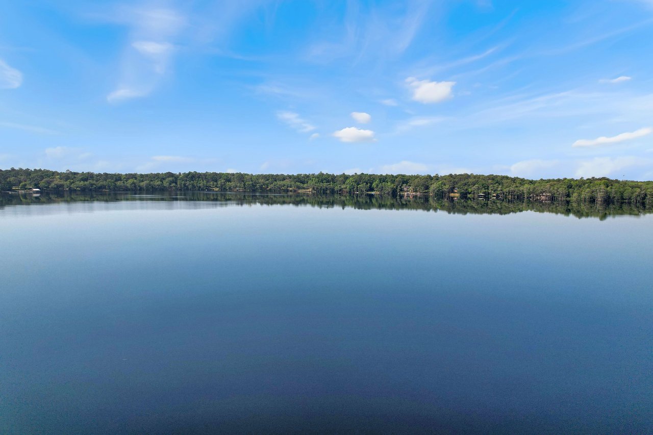 A wide view of the Lake Bradford with a clear blue sky above. The lake is surrounded by trees, giving a peaceful and natural appearance.