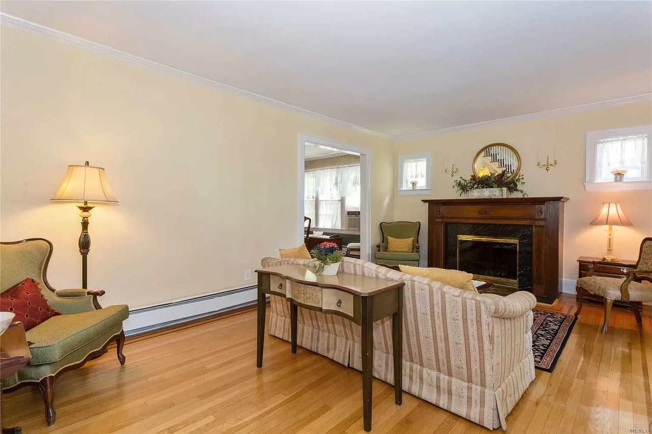Living room with hardwood floors, a dark wood fireplace, and a patterned sofa.