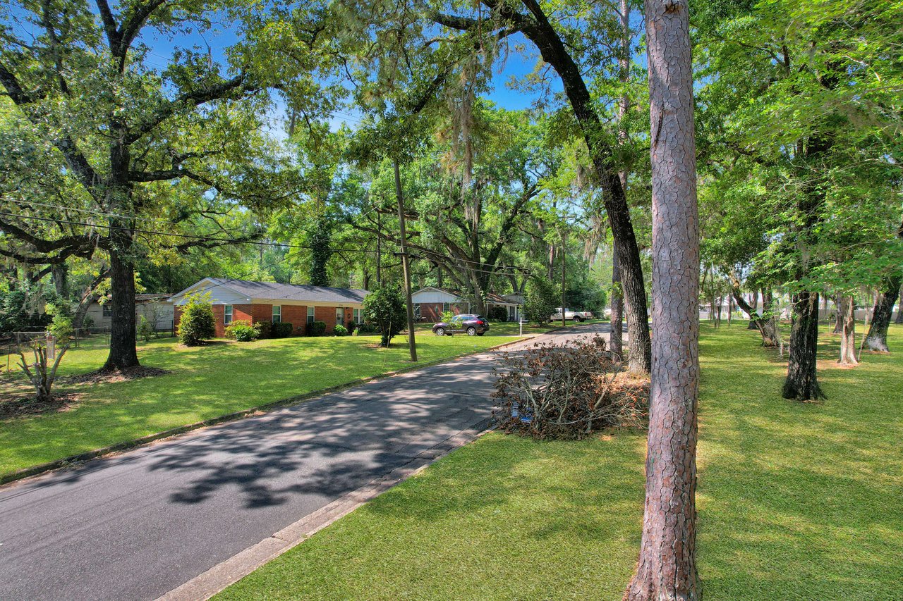 A view of a residential street within a neighborhood in Marby Park. The street is lined with large trees, providing ample shade and a picturesque setting.