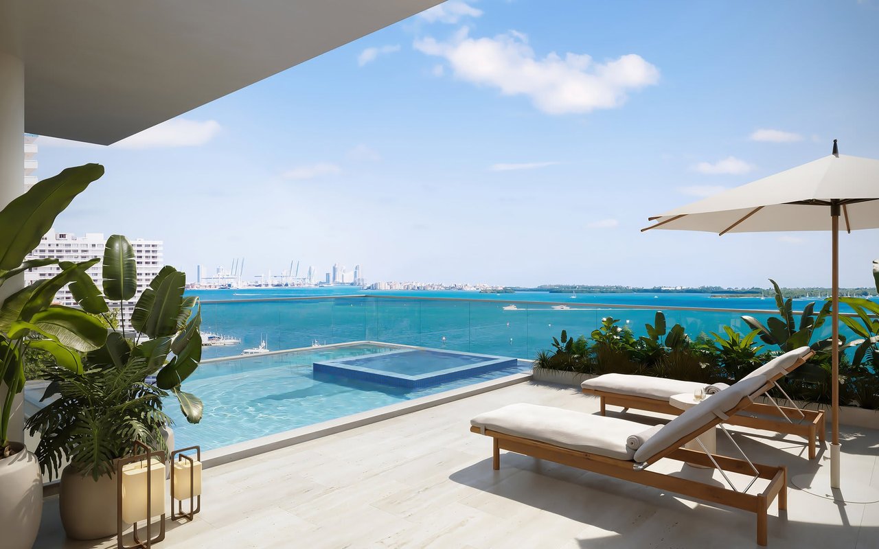 Miami residence terrace with a pool, loungers, tropical plants, and a view across Biscayne Bay.