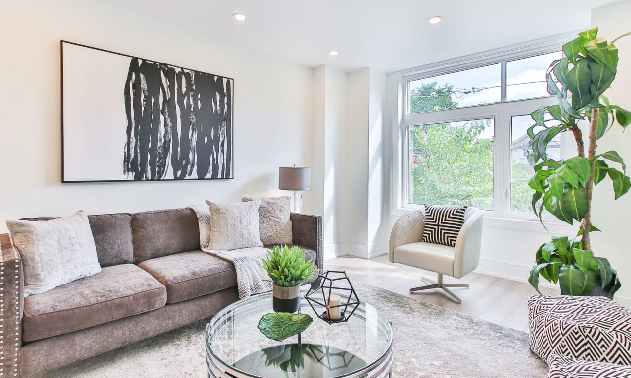 A furnished living room with a couch, chair, coffee table, and artwork.