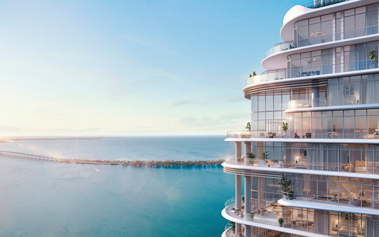 St. Regis Miami Residences rendering overlooking Biscayne Bay, with curved glass balconies and a distant causeway.