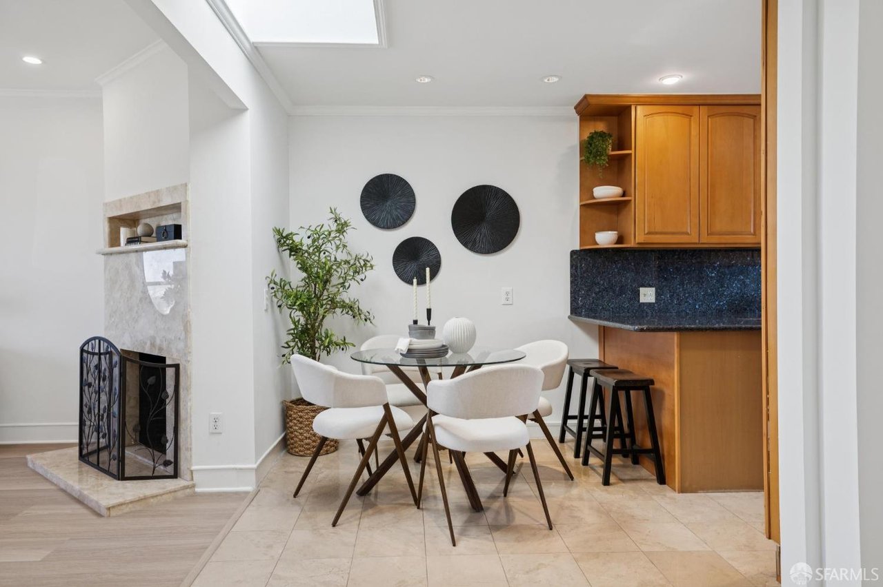 Dining area with a round glass table beside a stone fireplace and built-in wooden bar.