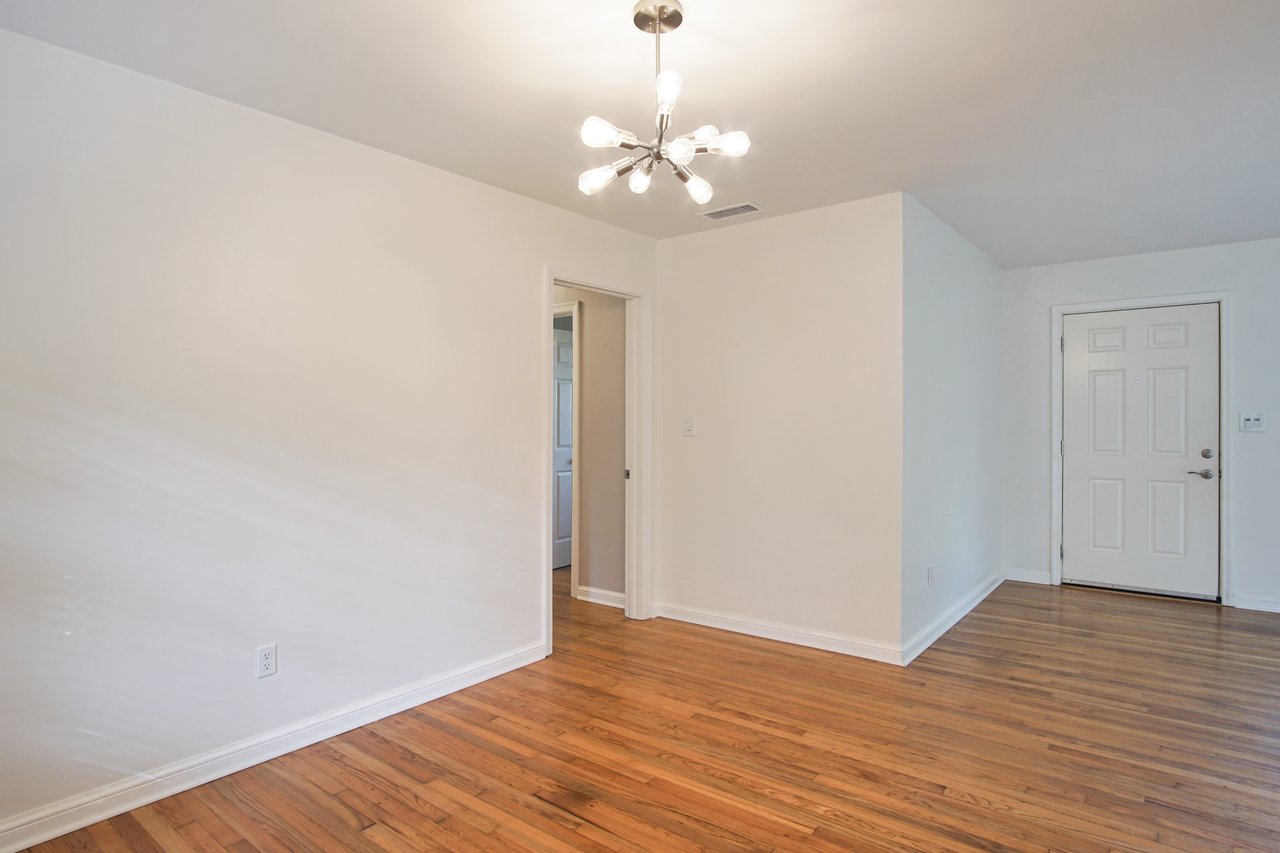 Empty room featuring hardwood floors and white walls, creating a bright and spacious atmosphere.