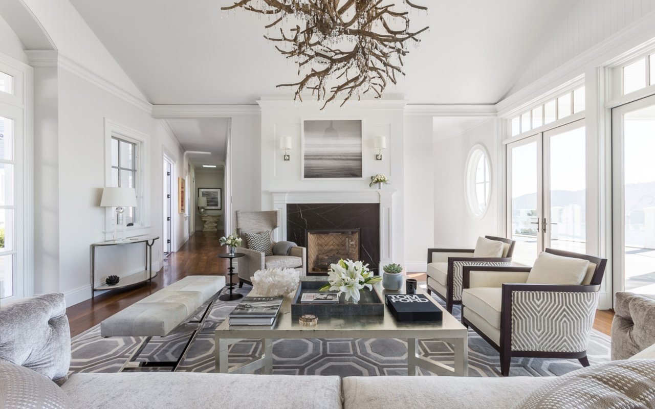 Staged living room with a black marble fireplace, neutral seating, and glass doors opening to a terrace.