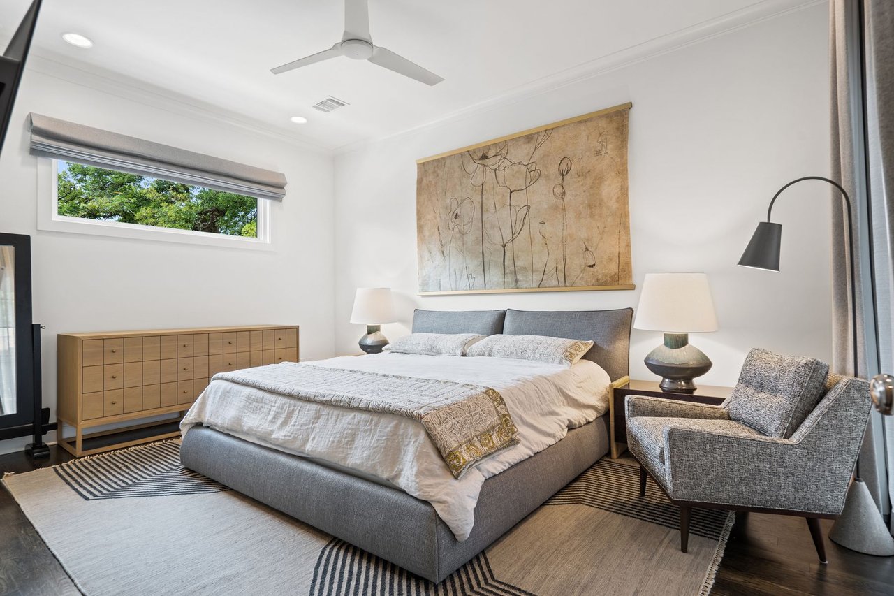 Guest bedroom with an upholstered bed, wood dresser, and area rug, furnished by Ashby Collective, at 2600 Westover Road in the Tarrytown neighborhood of Austin.
