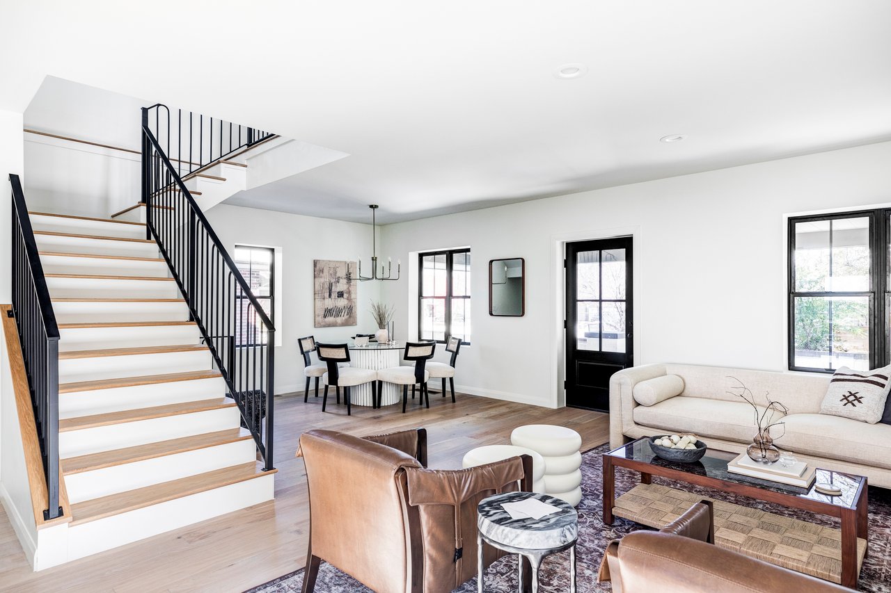 Open living room with dining area in the front corner and a stairway leading to the upstairs