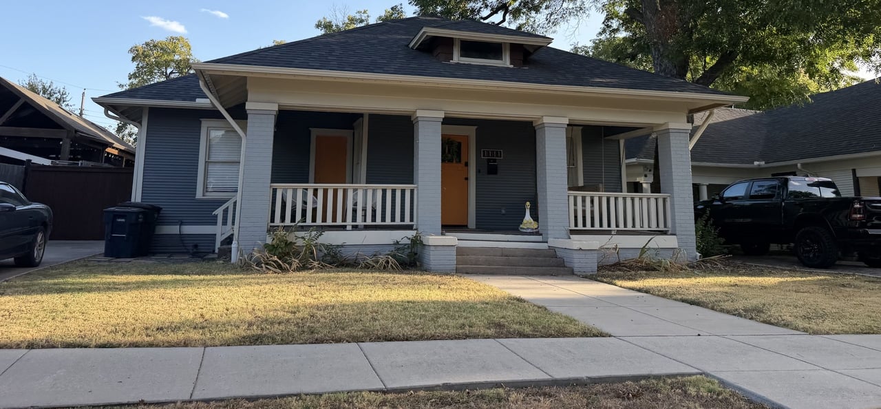 Blue bungalow with a broad covered porch, white columns, and a front lawn.
