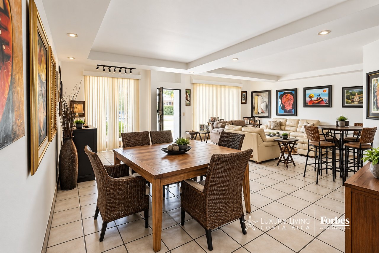 Open-plan dining and living room with woven chairs, cream sofas, and framed artwork.