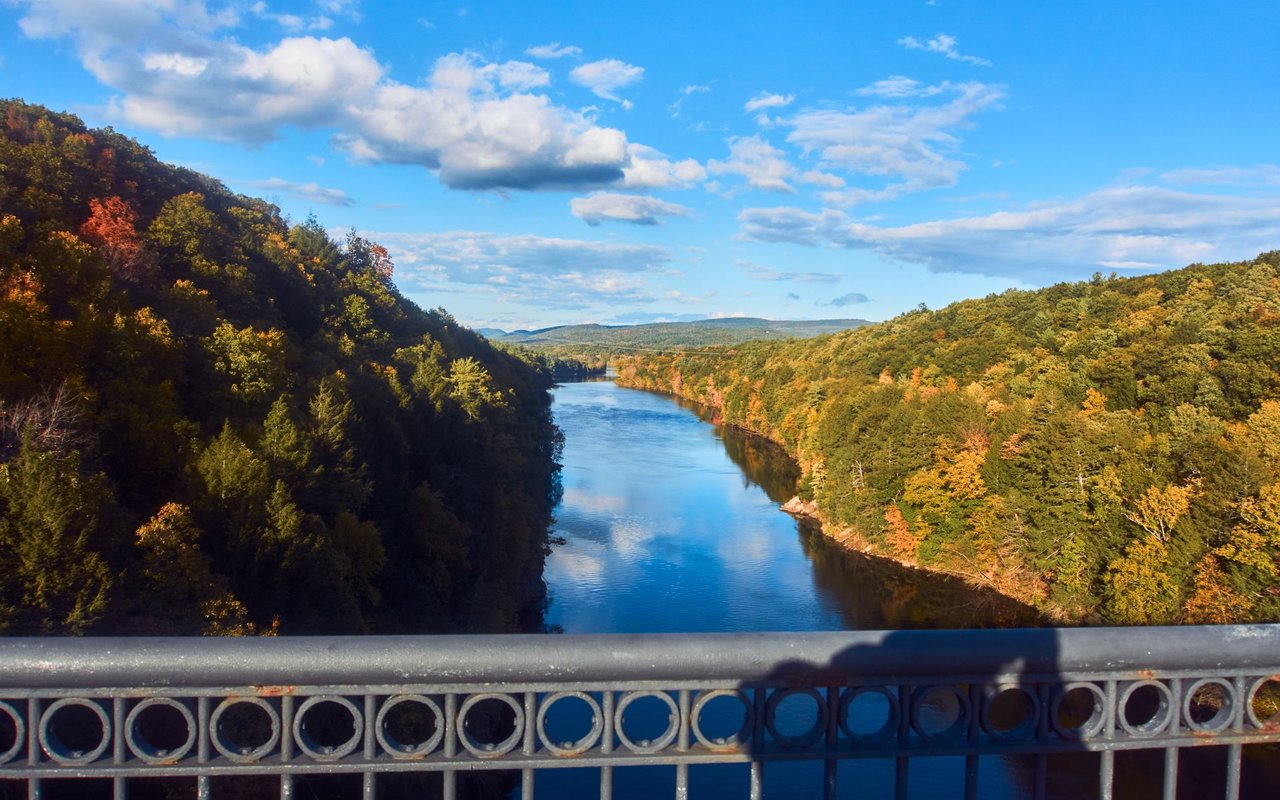 Athletes competing in the Great River Challenge Triathlon in Connecticut, with participants running, biking, and paddling along the scenic Farmington River backdrop.