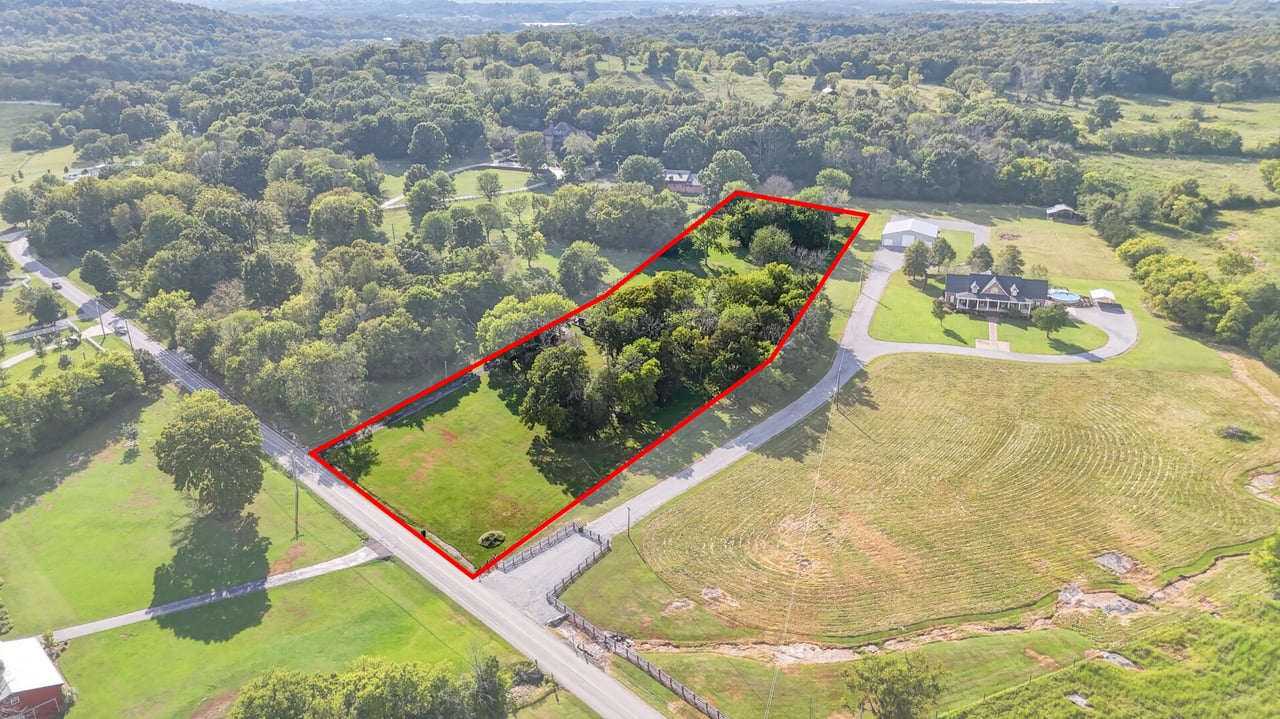 Aerial view of a rural property outlined in red, with a grassy entrance and a wooded interior.