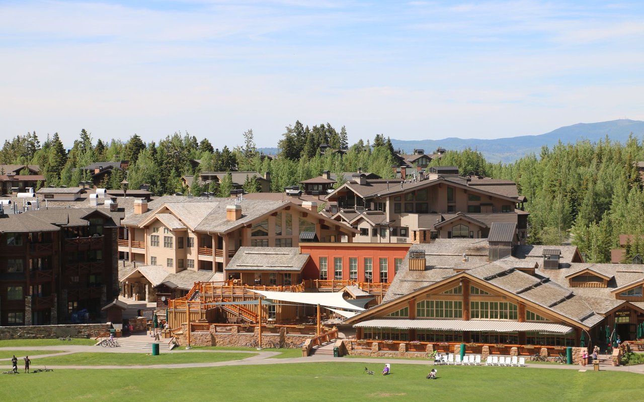 Lower Deer Valley resort buildings with a green lawn and mountain backdrop