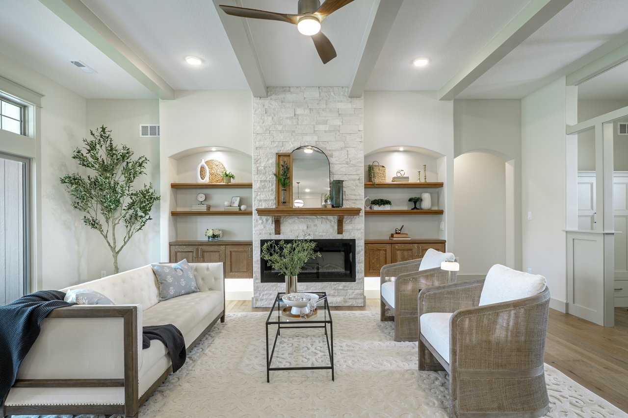 Living room with a white stone fireplace, built-in wood shelving, and a vaulted beamed ceiling.