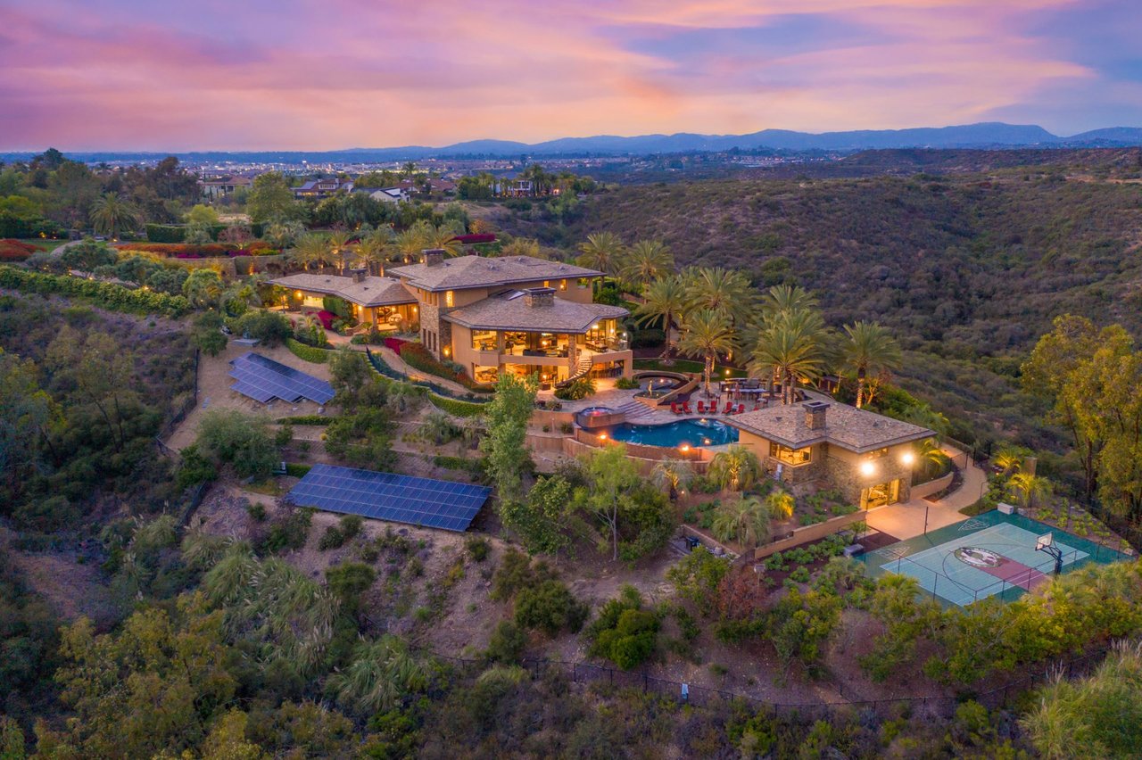 Luxury hillside estate in Del Mar Mesa, San Diego, featuring pool, solar panels, basketball court, and canyon views at sunset—ideal for high-end buyers seeking privacy and elegance.
