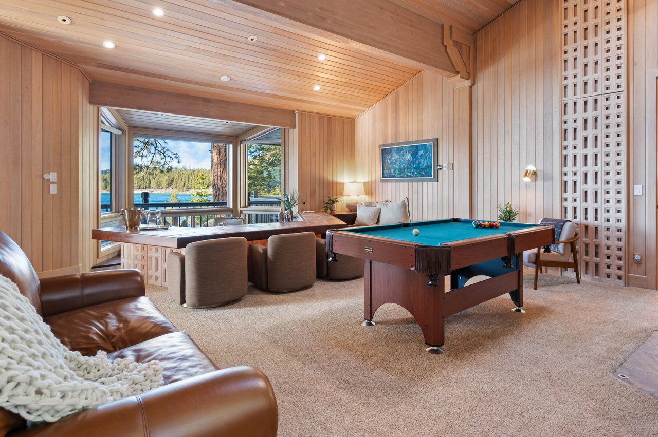 Game room with a pool table and lake views through large windows.