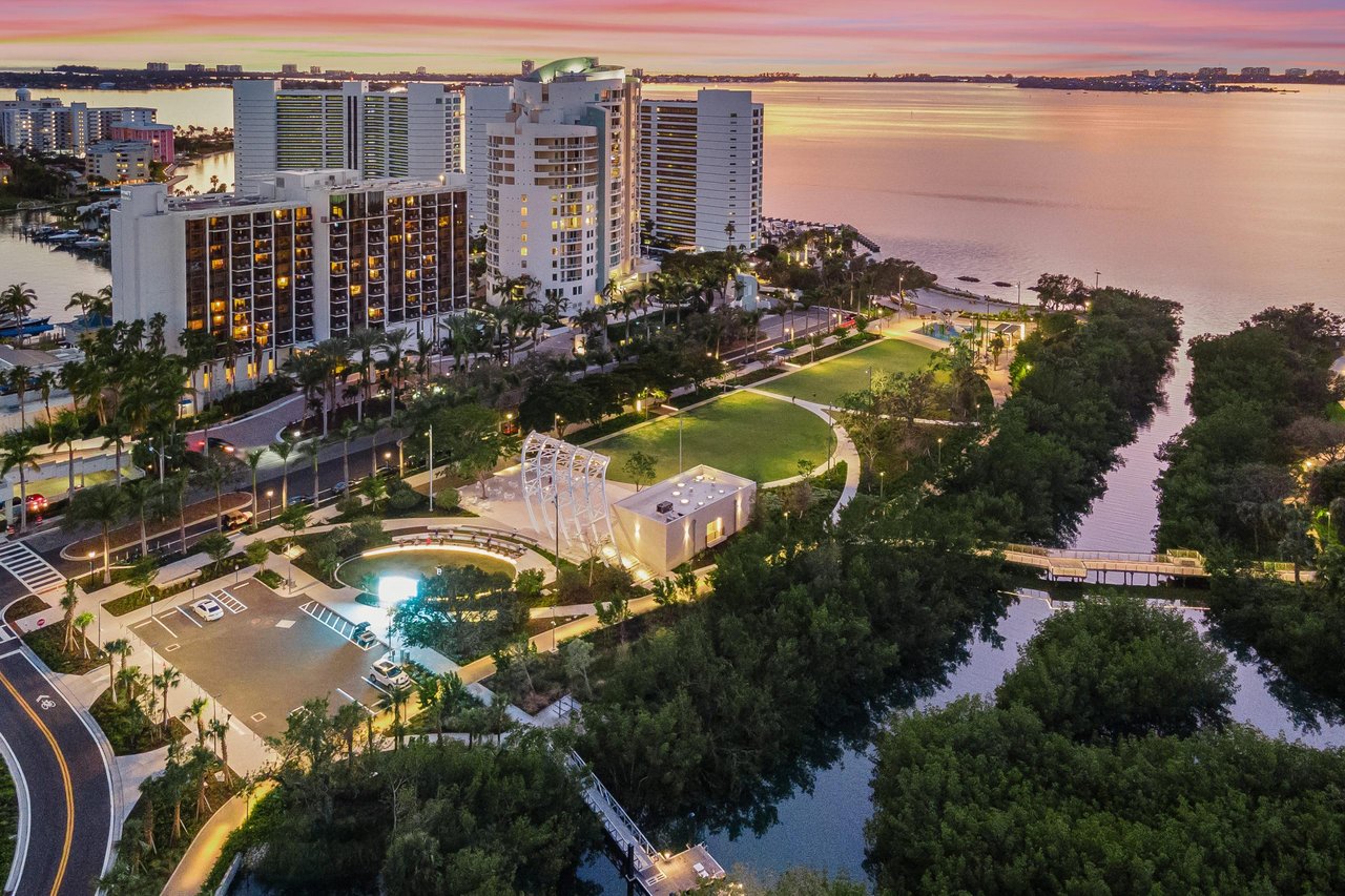 Downtown Sarasota waterfront condos at dusk, with high-rises, a landscaped park, and bay views.