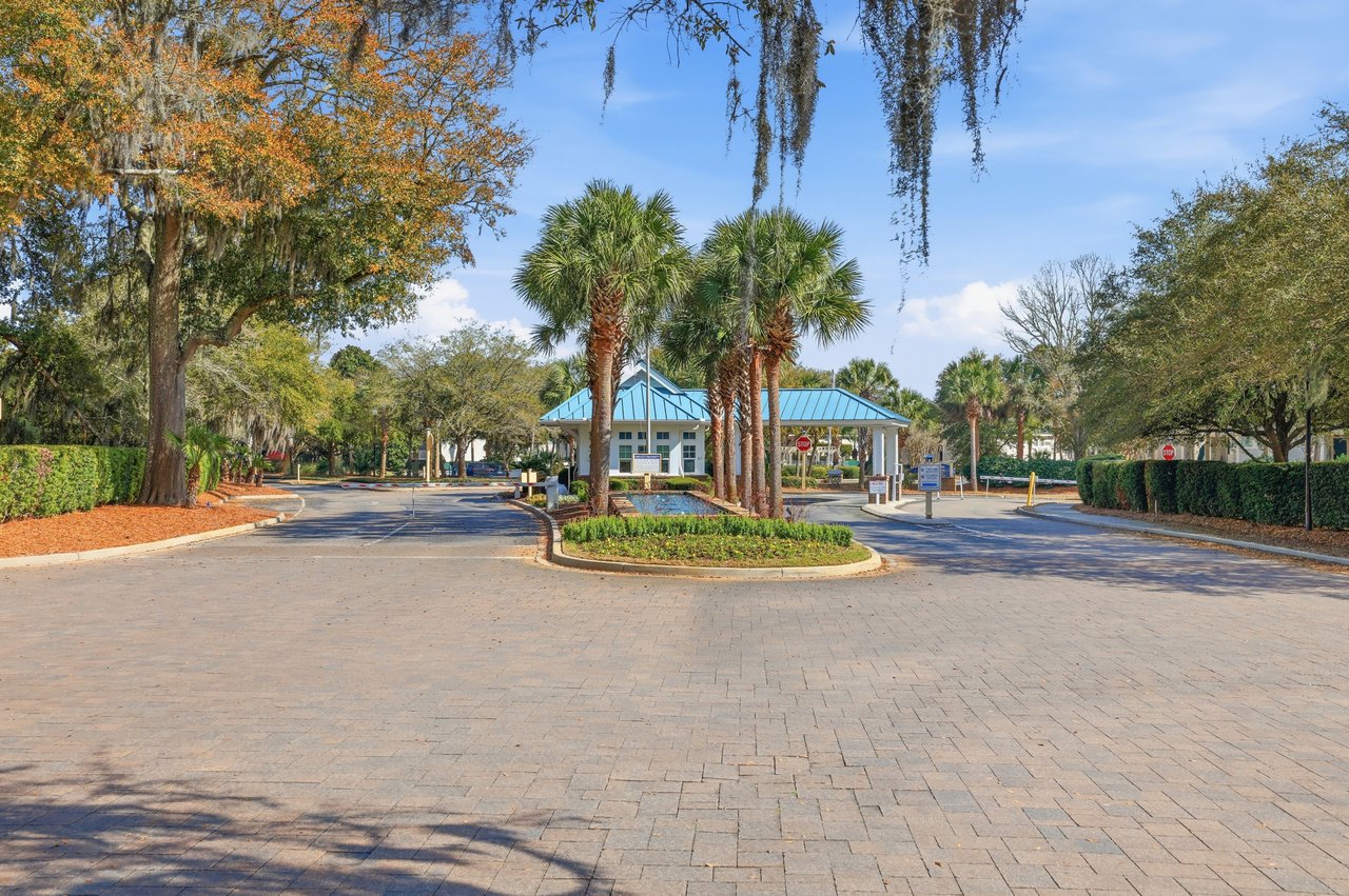Heron Marsh Villas entrance with a blue-roofed gatehouse, palm trees, and landscaped median.