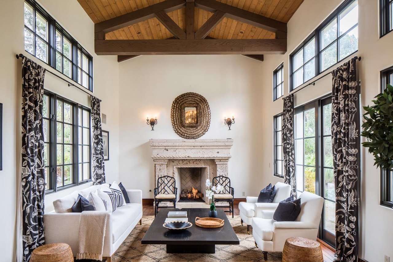Living room with vaulted wood ceiling, tall windows, and a stone fireplace.