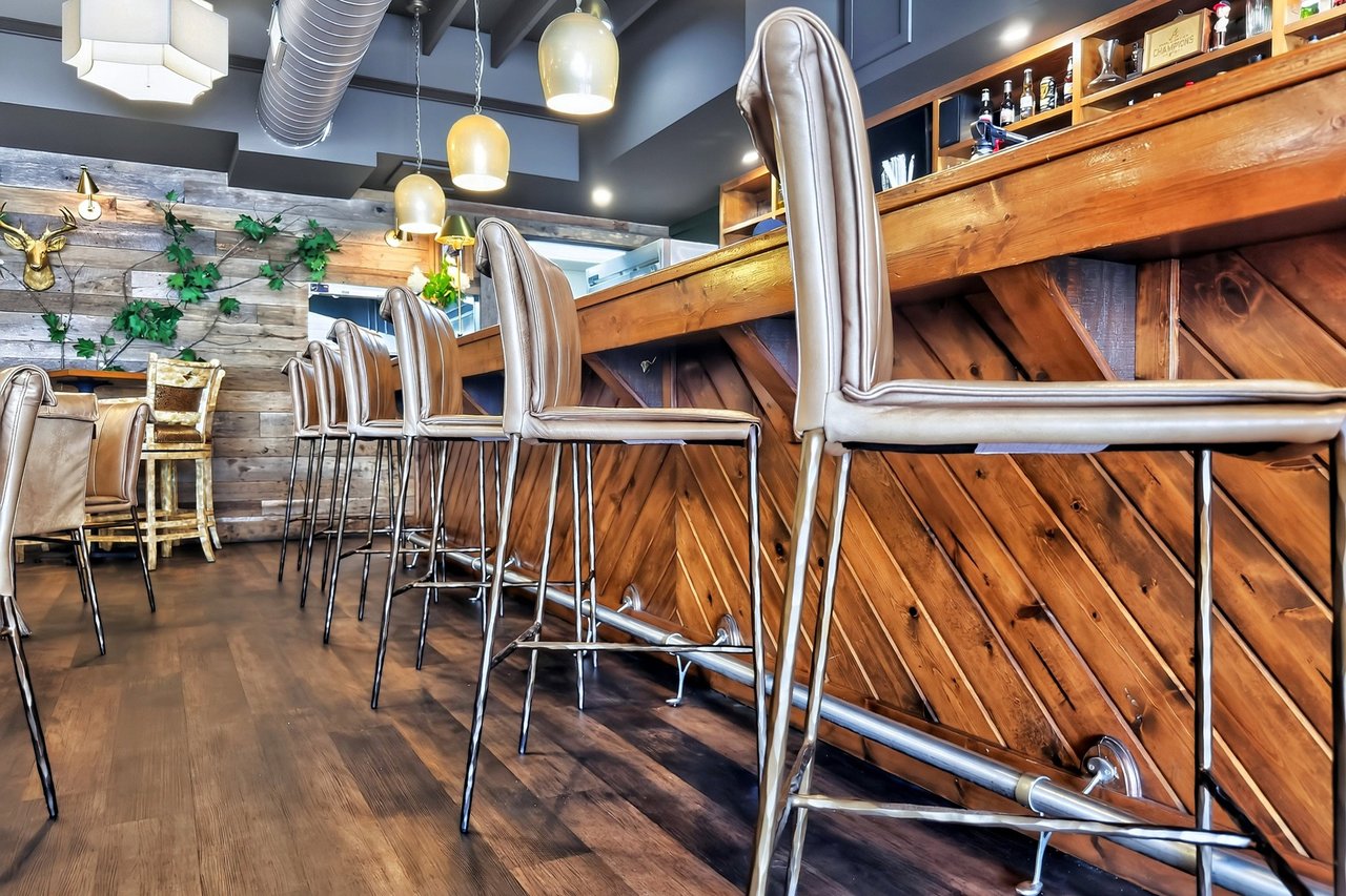 Restaurant bar with tall leather stools and rustic wood paneling.