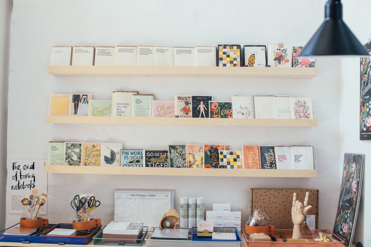 Colorful greeting cards and stationery displayed on wooden wall shelves in a shop.