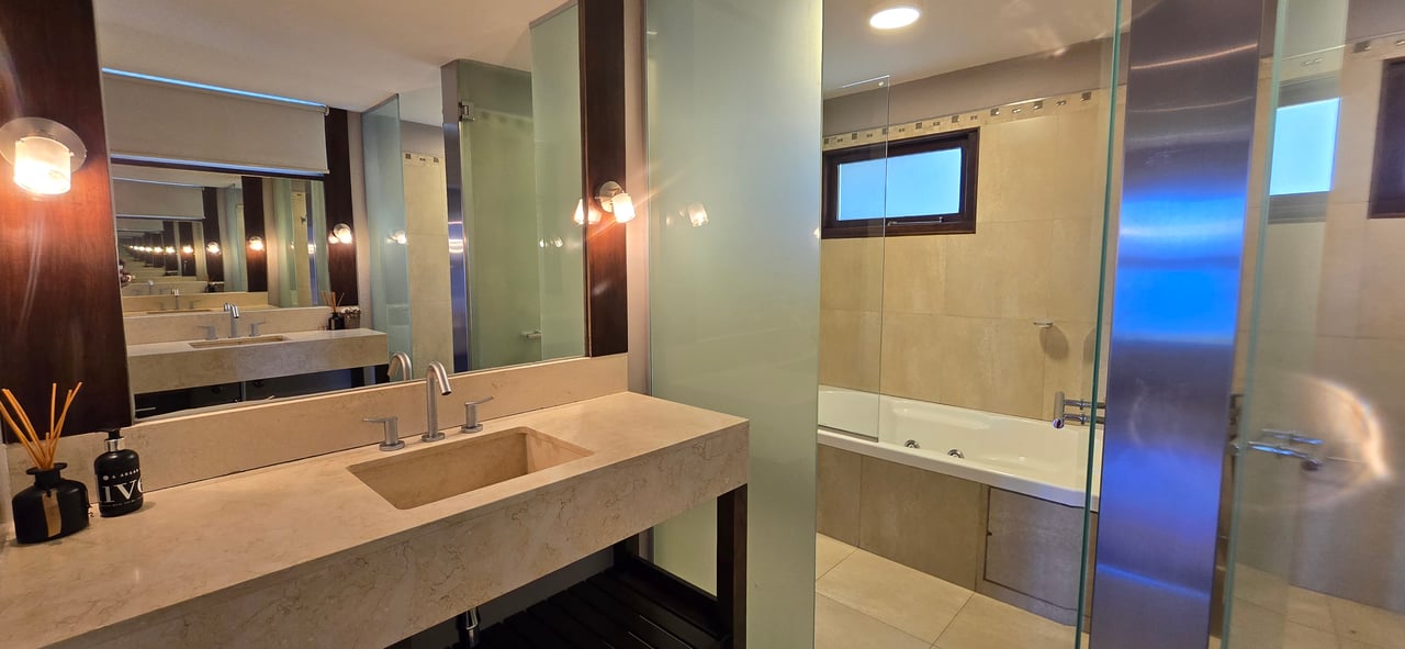 Bathroom with a stone vanity and sink beside a glass-enclosed bathtub.