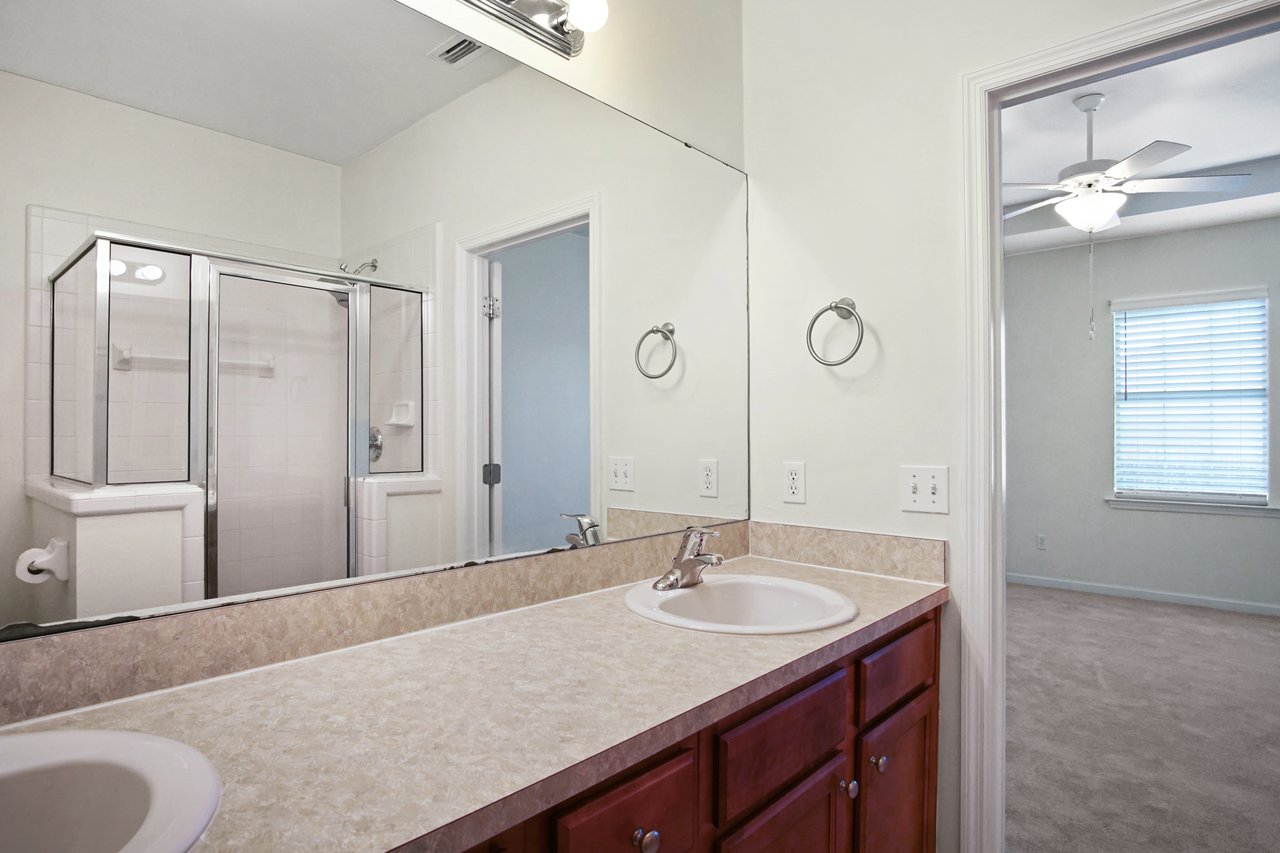 Primary bathroom at 5441 Hampton Hill Circle, Tallahassee, Florida 32311 with dual vanity, large mirror, and glass walk-in shower.