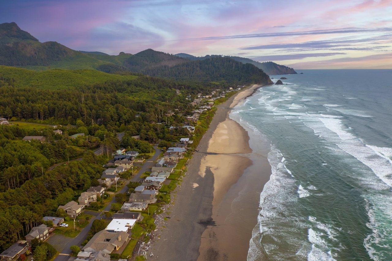 Aerial view of Arch Cape homes at sunset with the grey ocean