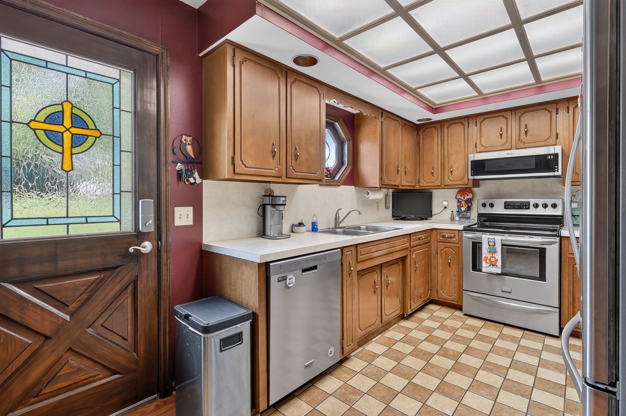 Kitchen with wood cabinets, stainless steel appliances, and a stained-glass door panel.