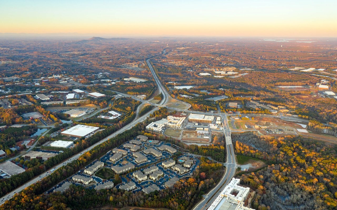 Aerial view of autumn neighborhoods, commercial buildings, and highways at golden hour.