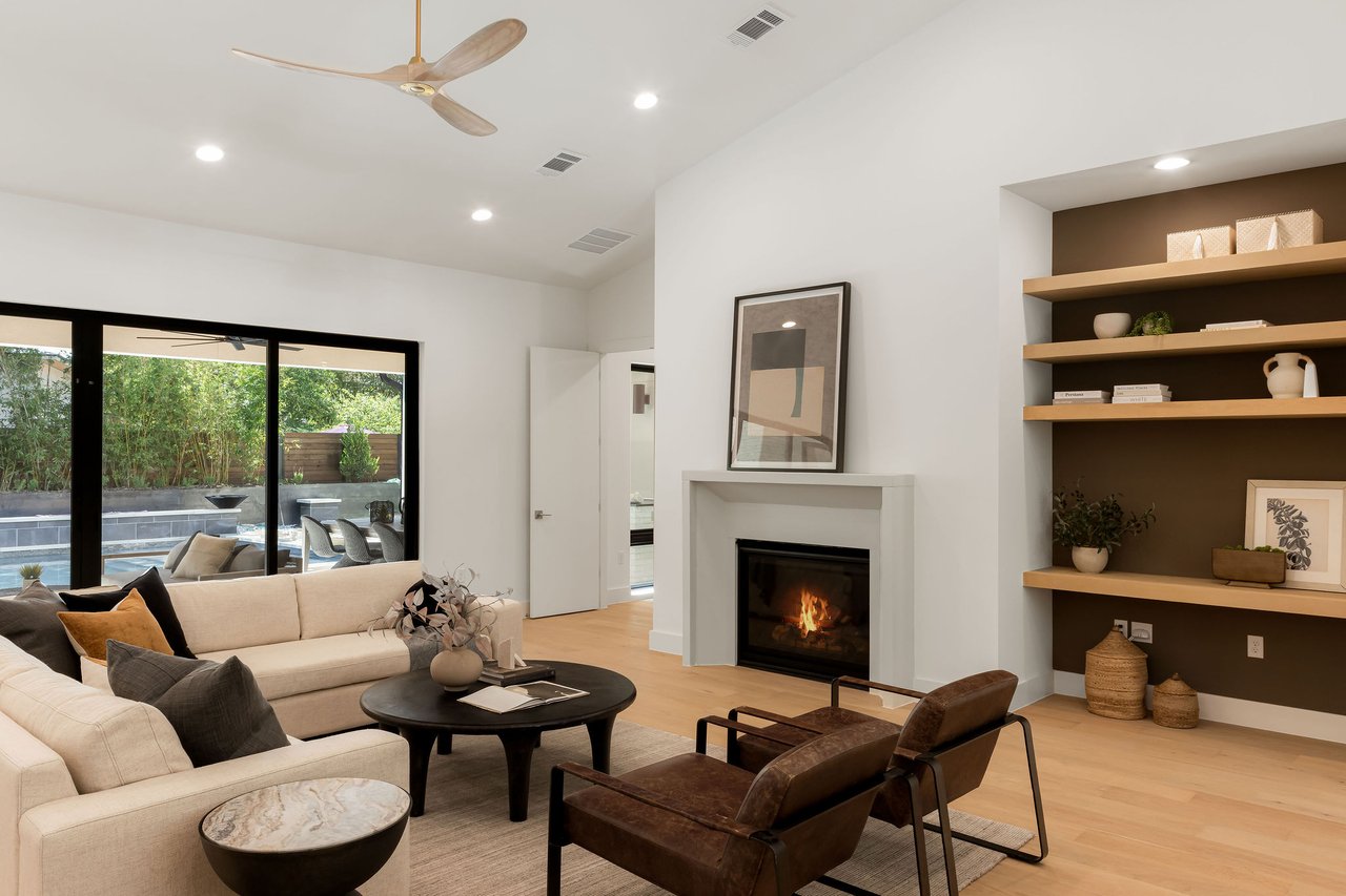 Great room at 1001 Bluebonnet Ln (Zilker, Austin) with built-in shelving, a gas fireplace, and sliding glass doors opening to the back patio.