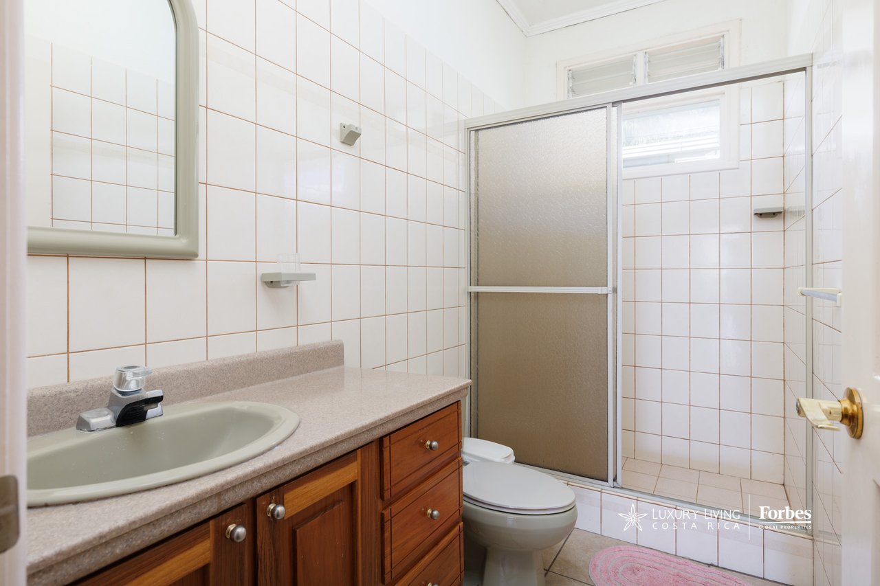 Bathroom with a wood vanity, tiled walls, and a frosted-glass shower enclosure.