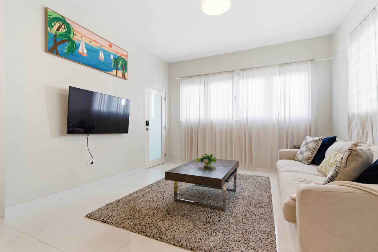 Living room with a beige sofa, wall-mounted television, and colorful sailboat artwork.