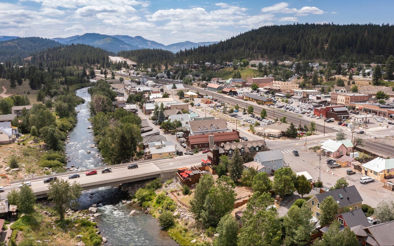 Aerial view of Truckee beside the river, with a bridge and forested mountains.