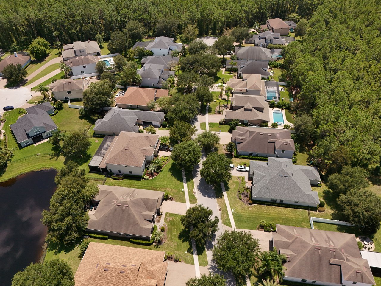 Aerial view of Austin Park homes beside a pond and dense woodland.