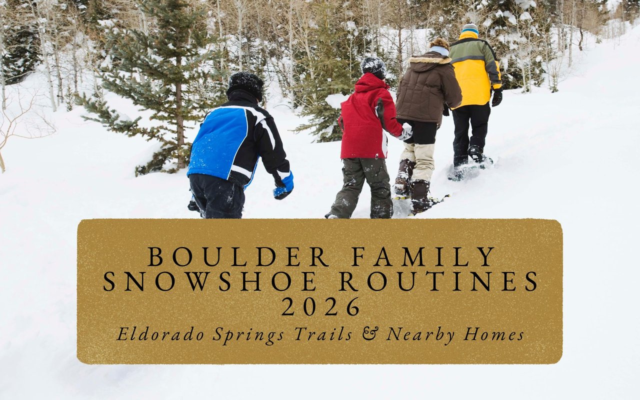 Family of four snowshoeing wide snowy trail with Boulder Flatirons in background, smiles and steaming breath visible.