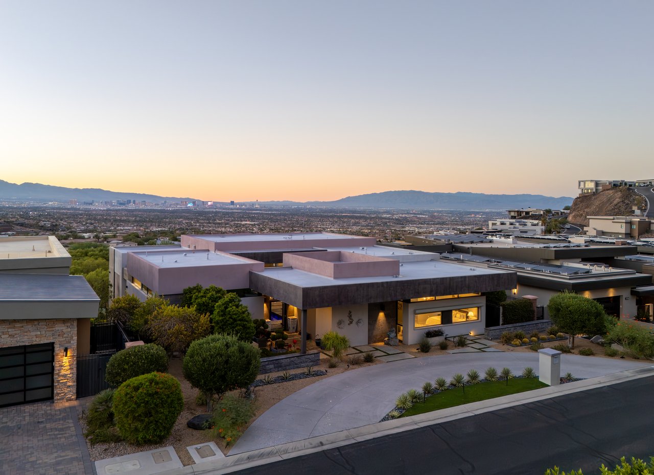 Dusk aerial of a modern luxury home above the Las Vegas valley and Strip skyline
