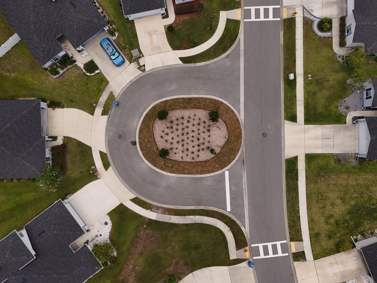 Aerial view of a residential cul-de-sac with a landscaped island and surrounding homes.