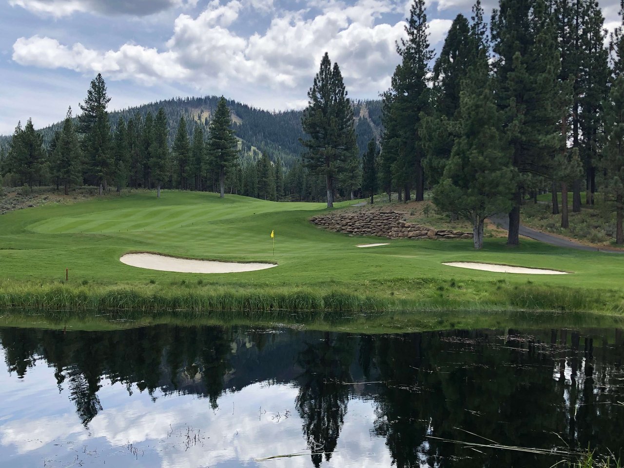 Scenic view of a pristine golf course near Lake Tahoe, surrounded by pine trees and mountains, highlighting luxury living near Lake Tahoe homes for sale.