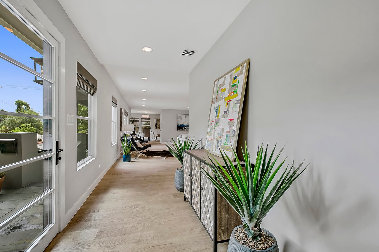 Entry hallway at 1004 Maufrais Street in Clarksville (Old West Austin), Austin, TX, with wide-plank white oak floors and a glass-paned front door opening to the living areas beyond.