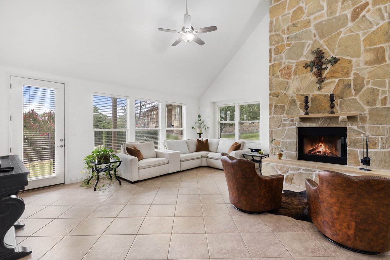 Living room with a tall stone fireplace, cream sectional, and brown leather chairs.